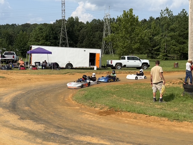 A group of karts rolling out onto the track past the haulers
