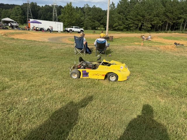 The yellow 10X kart parked on the grass beside the track