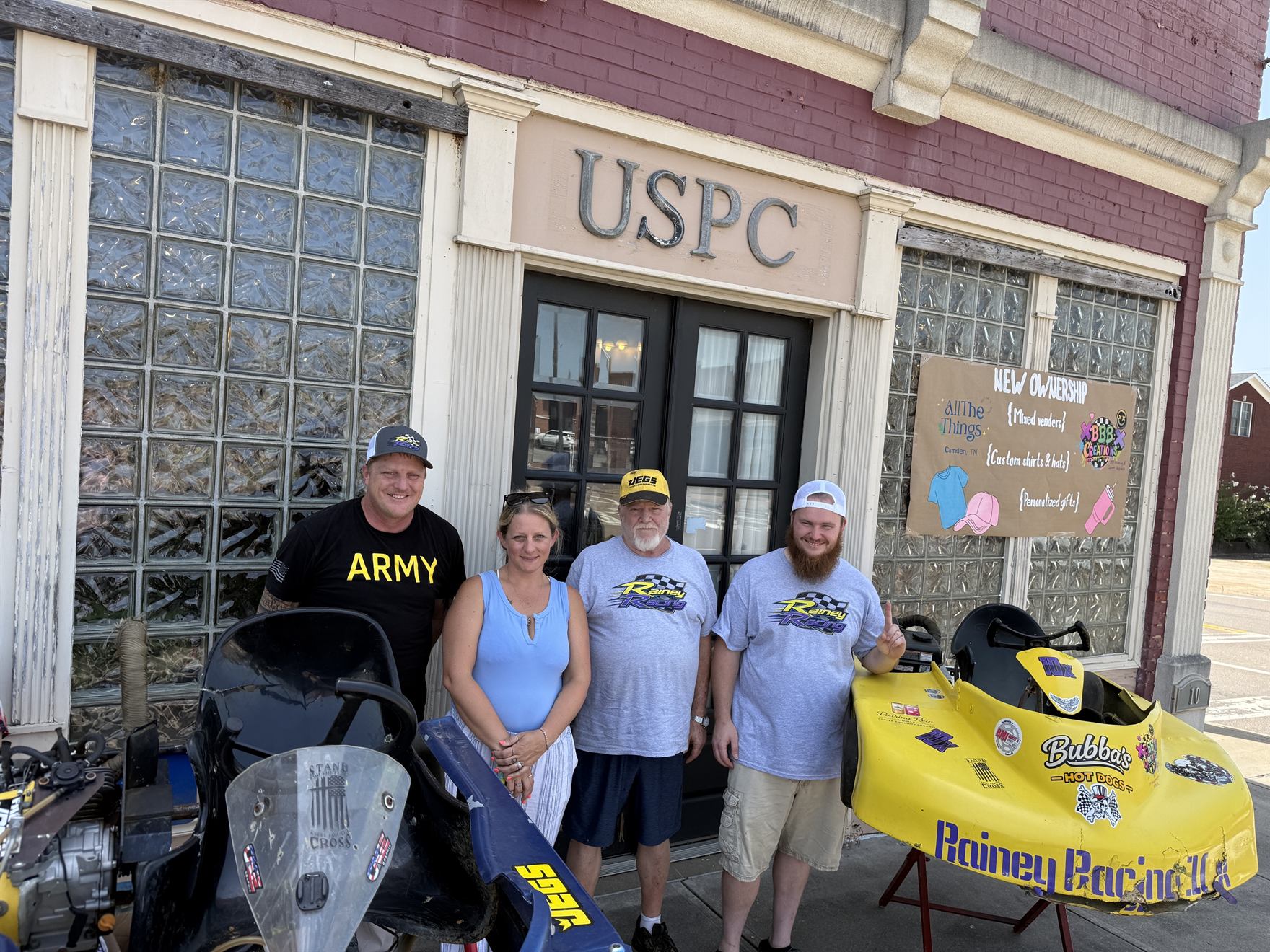 Ronnie Rainey, Brandi Bath, Ronnie Rainey Sr. and Travis Rainey standing between the two karts outside the shop