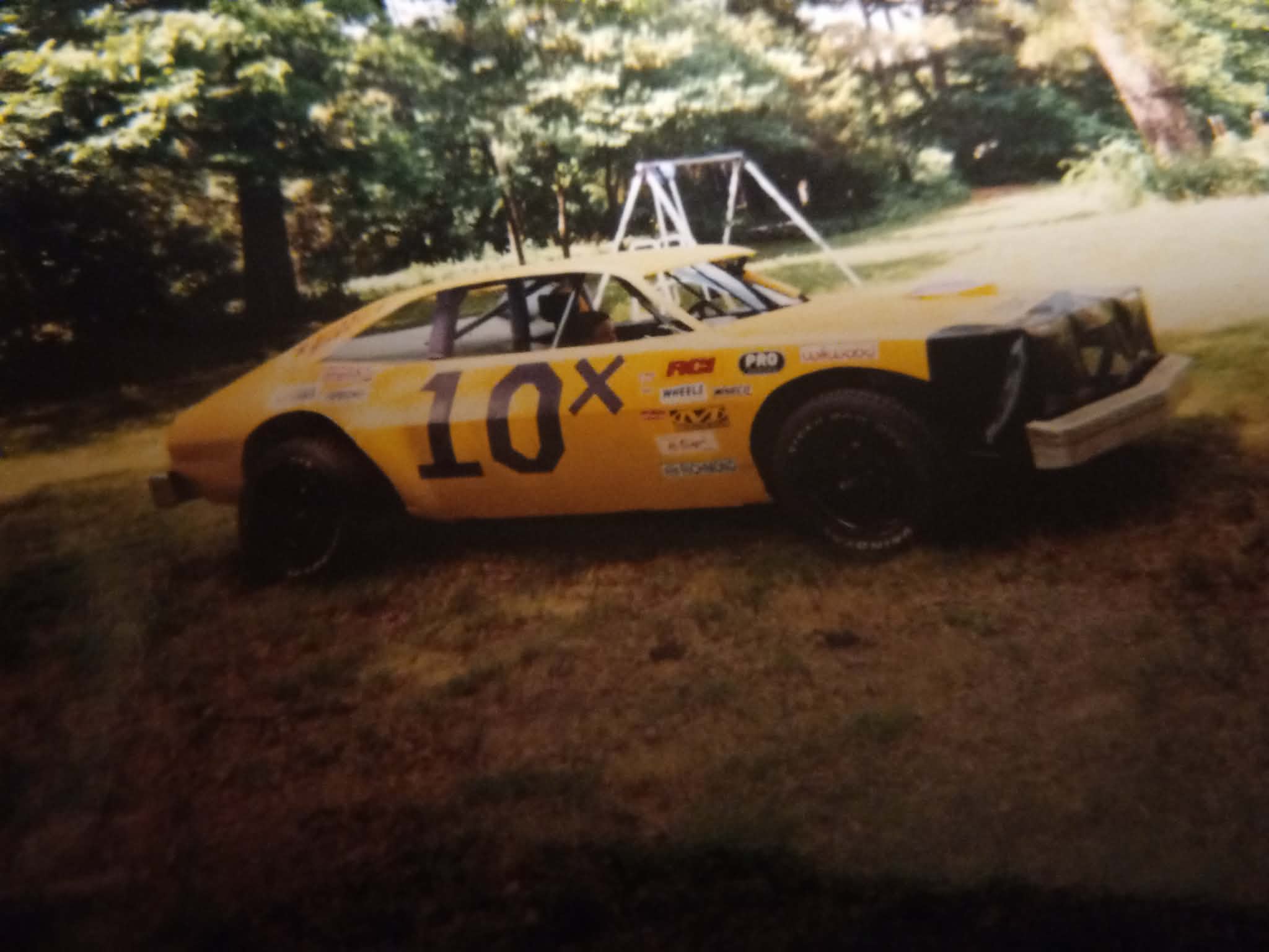 Ronnie Rainey Sr.'s bright yellow Mini Stock dirt car with bold purple 10X numbers on the door, parked in the yard in the early 2000s