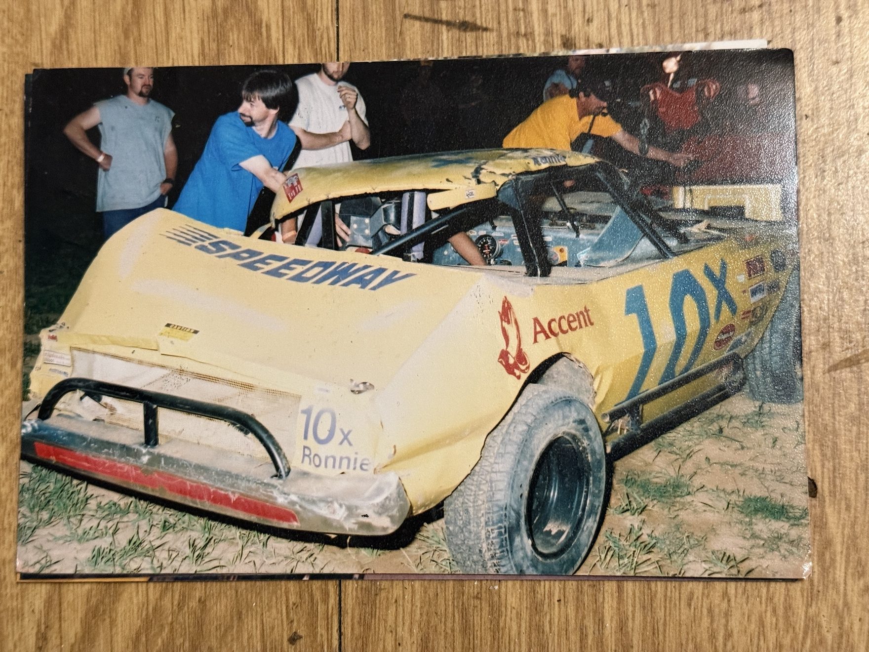 The 10X Mini Stock in the pits at night after Ronnie Rainey Sr. wrecked it, hood off and the crew working on the car