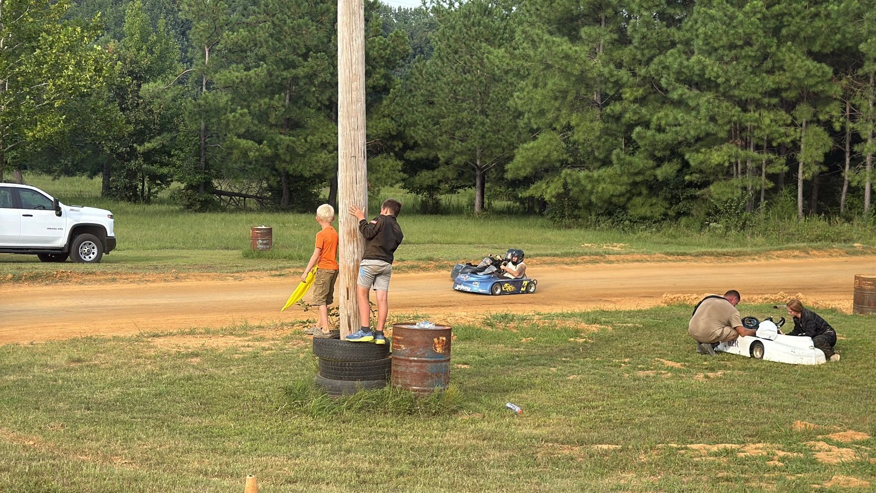 Ronnie's blue 3 kart on track at Camden Speedway with kids watching from the tire stack