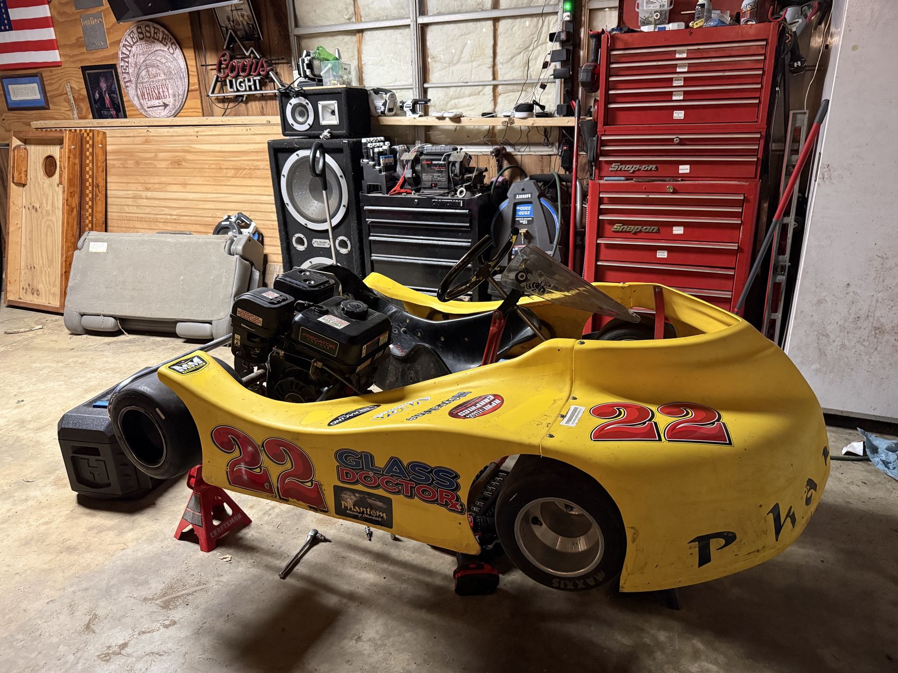 The new yellow Phantom kart on stands in the shop beside the tool boxes