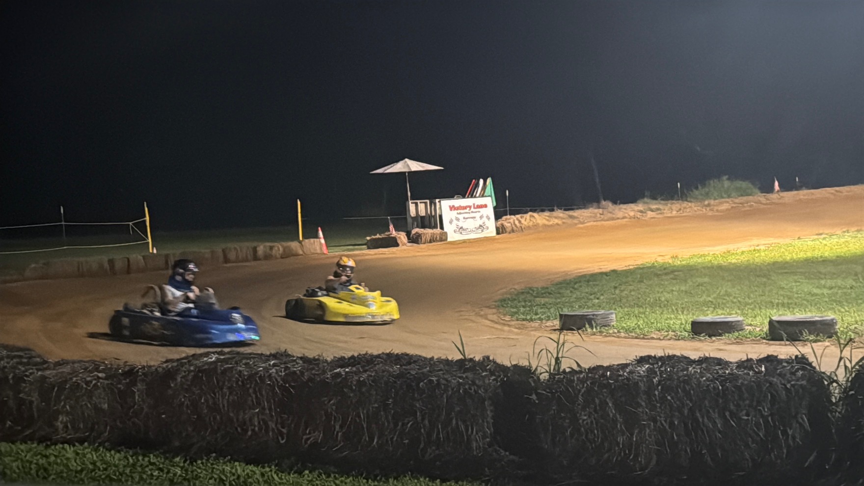 Ronnie's blue 3 leading Travis's yellow 10X through a corner at night at Adjoining Hearts Raceway
