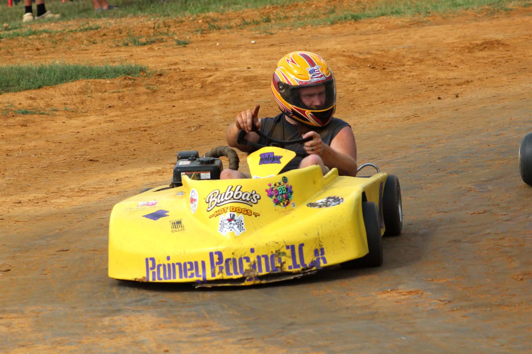 Travis Rainey driving the yellow No. 10X kart on the dirt at Camden Speedway