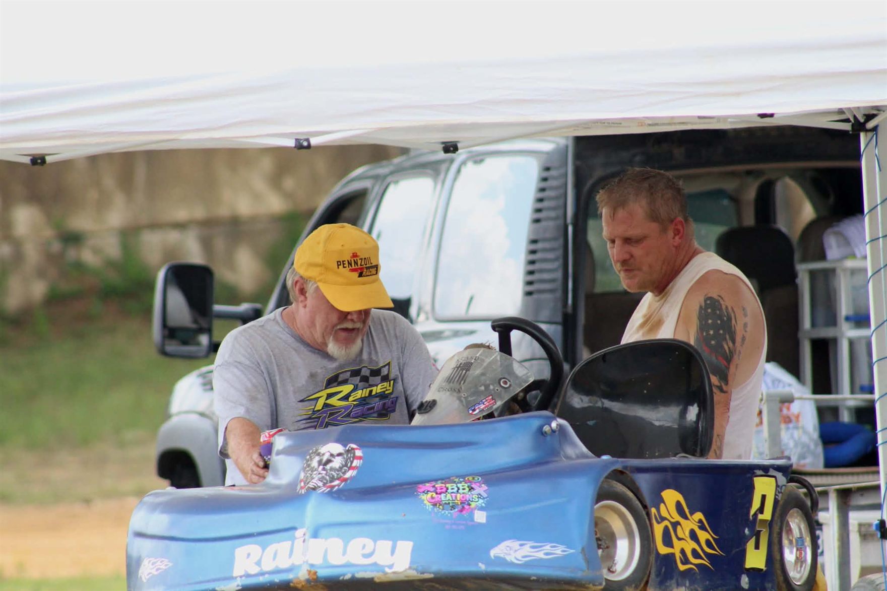 Ronnie Rainey Sr. in his Rainey Racing shirt working on the No. 3 kart alongside his son Ronnie