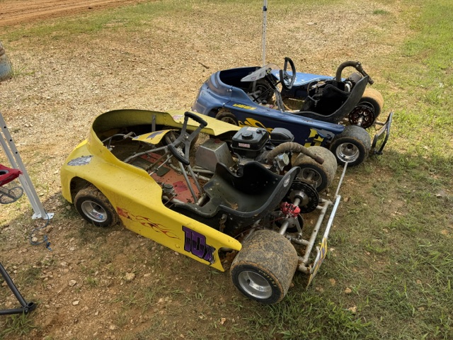 The yellow 10X and blue 3 karts nose to tail on the grass in the pit area